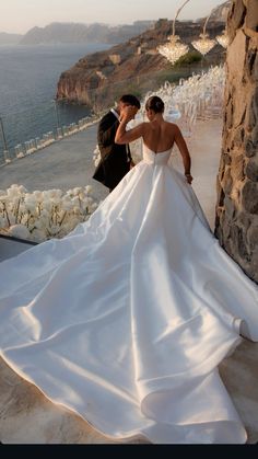 the bride and groom are posing for pictures on their wedding day in front of an ocean view