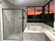 a bathroom with a tub, sink and large window overlooking the mountains at sunset or dawn