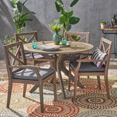 an outdoor table and chairs with potted plants in the corner on a patio rug