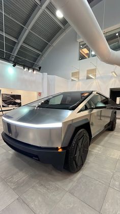 an electric car is parked in a large room with white walls and ceiling lights above it