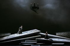 two people standing on top of wooden beams in front of a dark sky with clouds