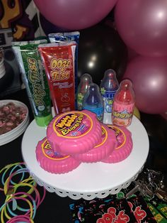 a birthday cake with candy and confection on it sitting on a table in front of balloons