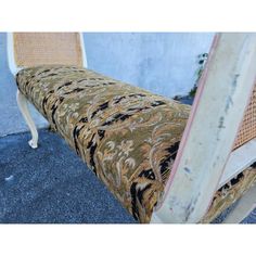 an old chair is sitting outside on the sidewalk next to a wall and cement floor