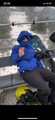 a man sitting on top of a snow covered ski lift holding his hands up in the air