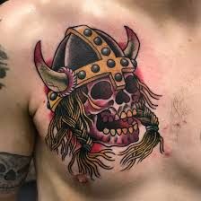 a man's chest with a skull wearing a crown and horns tattoo on it