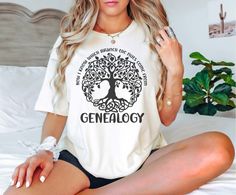 a beautiful woman sitting on top of a bed wearing a t - shirt that says genialogy