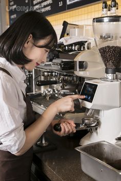 a woman operating a coffee machine in a restaurant or cafe setting, while looking at the screen