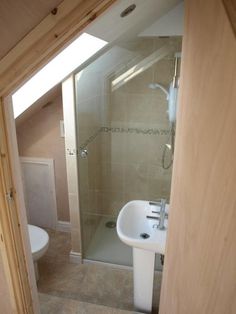 a bathroom with a sink, toilet and shower stall in the corner is seen through an open door