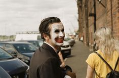 a man dressed as the joker standing next to a woman