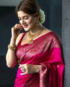 a woman in a pink sari and gold jewelry is talking on her cell phone