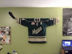 a hockey jersey hanging on the wall in a room with a laptop and other items