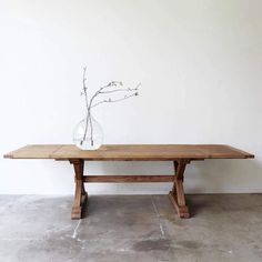 a wooden table with a vase on top of it and a branch in the middle