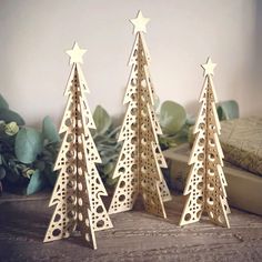 three wooden christmas trees sitting on top of a table next to a book and plant