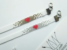 two white bracelets with red hearts on them