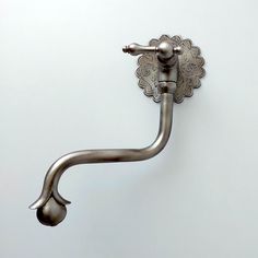 a metal hook on the side of a wall with an ornate design and flower decoration