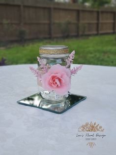 a pink flower in a mason jar on a table