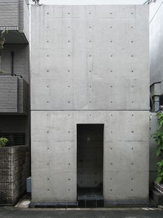 an apartment building that is made out of concrete and has a door in the middle