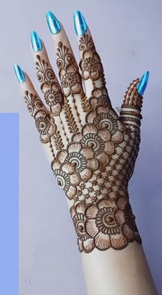 a woman's hand with blue nails and henna on her hands, showing the intricate design