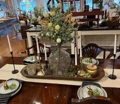 a dining room table set with plates and flowers on the centerpiece, along with other place settings