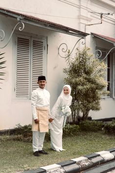 two people standing in front of a white building