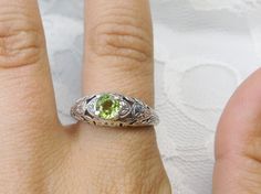 Natural Peridot Ring Etched Wedding Design#160 Made To Order Here we have a Victorian/Edwardian reproduction ring in sterling silver with a stunning natural peridot gemstone. This full cut round peridot gem is 6mm in diameter. The inside of the band is marked 925 for sterling. Notice the beautiful floral design of the silver filigree setting and band. This is a lovely rendition of an Antique filigree ring; and it is ready to wear. A gift ring box is included and all rings are shipped in the box Green Engraved Wedding Rings, Lime Green Wedding Rings, Lime Green Round Jewelry For Wedding, Ornate Green Wedding Ring, Vintage Peridot Rings For Wedding, Antique Filigree, Sterling Silver Filigree, Peridot Gemstone, Peridot Ring