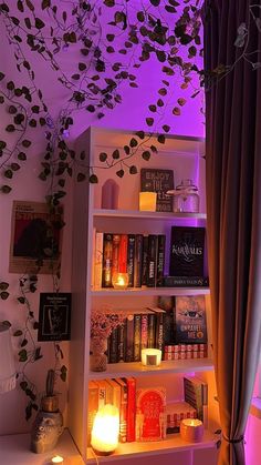 a bookshelf filled with lots of books next to a purple lit tree branch