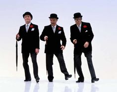 three men in suits and top hats holding an umbrella