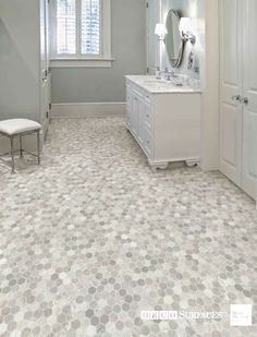 a large bathroom with white cabinets and gray flooring, along with an oval patterned tile pattern on the floor