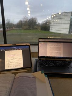 two laptops sitting next to each other on top of a table near a window