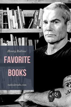 a man sitting in front of a bookshelf with his arms crossed and looking at the camera