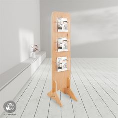 a wooden magazine rack with four magazines on it in a white room, next to a window