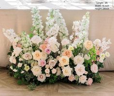 flowers are arranged on the floor in front of a table with white and pink flowers