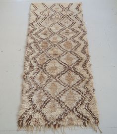 a brown and white area rug with fringes on the floor next to a wall