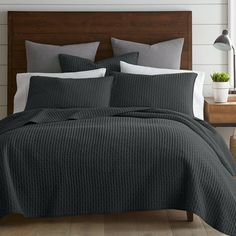 a bed with grey and white comforters in a bedroom