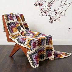 a crocheted blanket sitting on top of a wooden bench