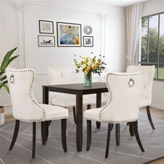 a dining room table with white chairs and flowers