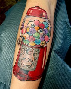 a tattoo on the arm of a person with a gumball machine in front of it