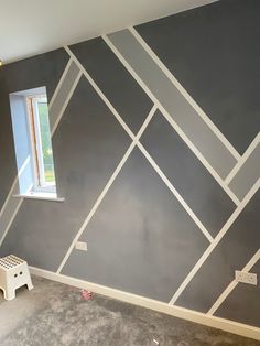 a room that has been painted with gray and white lines on the wall, along with a window