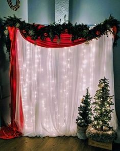 christmas decorations and lights are on display in front of a white curtain with red trim