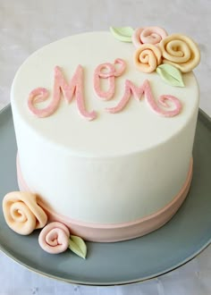 a white cake with pink icing and flowers on it's side, sitting on a plate