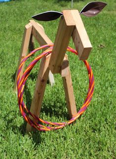 a wooden horse with two colored cords on it's back legs in the grass