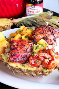 a pineapple with meat and vegetables on it sitting on a plate next to a bottle of booze