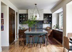 a kitchen with wooden floors and black cabinetry has an island in the middle that is surrounded by bar stools