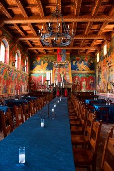 an empty dining room with blue tablecloths and chandeliers