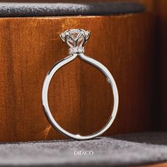 a diamond ring sitting on top of a wooden stand