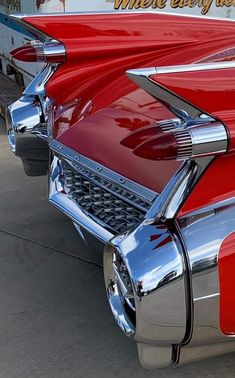 the front end of an old red car with chrome paint and lettering on it's hood