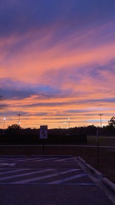 an empty parking lot with the sun setting in the background