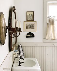 a white sink sitting under a bathroom mirror next to a wall mounted faucet