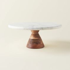 a white marble topped table with wooden base on a plain surface, against a neutral background