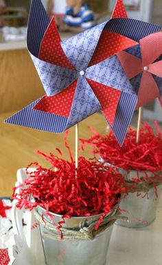 red, white and blue pinwheels are placed in buckets on a table